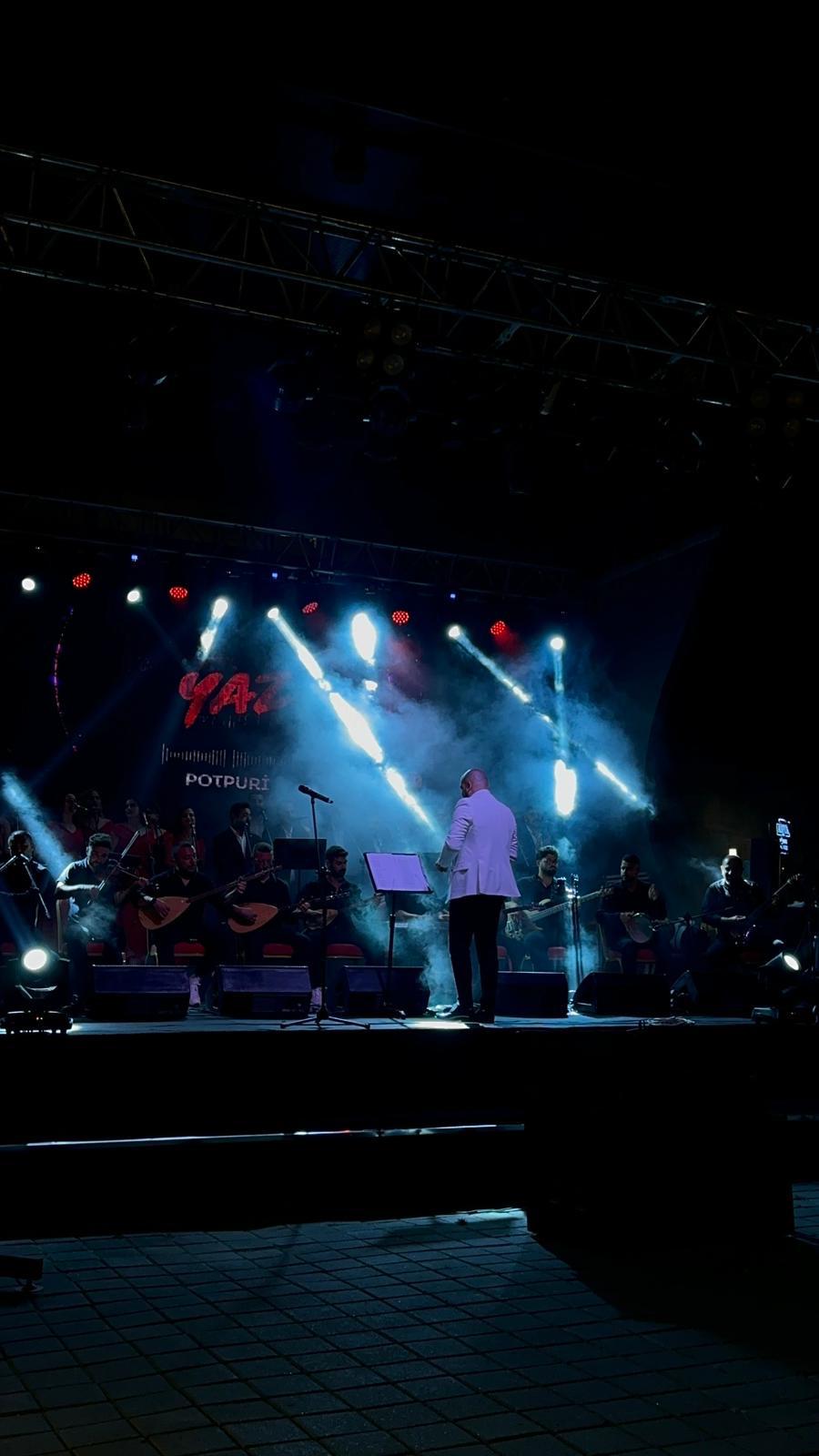 Mavi sahne ışıkları altında şef, koro ve orkestra
